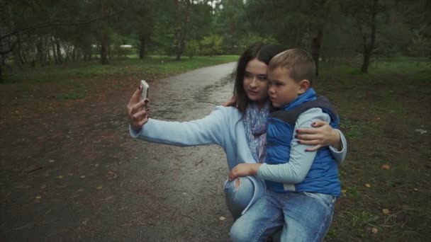 Moeder en zoon maken selfie in het najaar park — Stockvideo