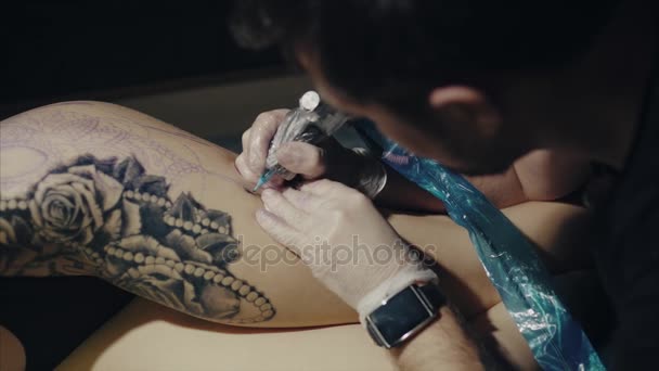 El primer plano de las manos del artista del tatuaje en guantes tatuando un patrón en el cuerpo — Vídeo de stock