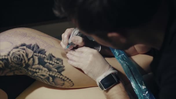 El primer plano de las manos del artista del tatuaje en guantes tatuando un patrón en el cuerpo — Vídeo de stock