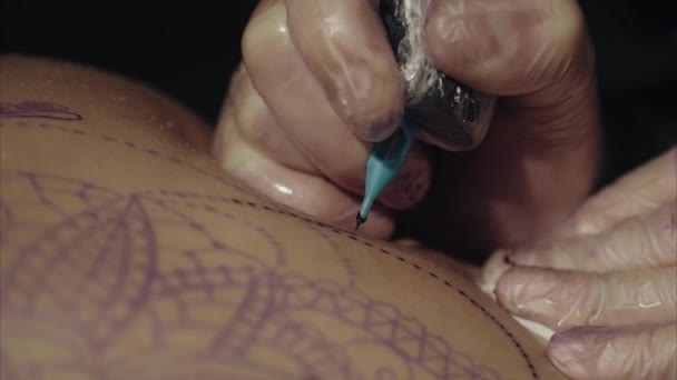 Primer plano de las manos del artista del tatuaje en guantes tatuando un patrón en la macro del cuerpo — Vídeos de Stock