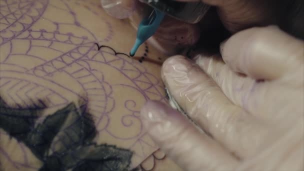 Крупный план рук татуировщика в перчатках, татуирующих рисунок на макросах тела — стоковое видео