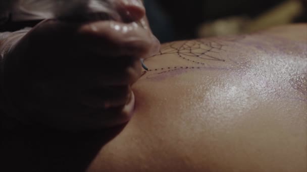 Close-up of hands of tattoo artist in gloves tattooing a pattern on body macro — Stock Video