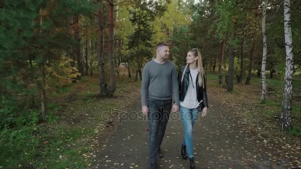 Ζευγάρι περπατά μέσα στο φθινόπωρο πάρκο — Αρχείο Βίντεο
