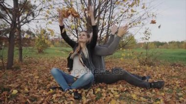 Sonbahar parkta oynarken ve atma genç mutlu çift yaprakları