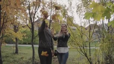 Sonbahar parkta oynarken ve atma genç mutlu çift yaprakları