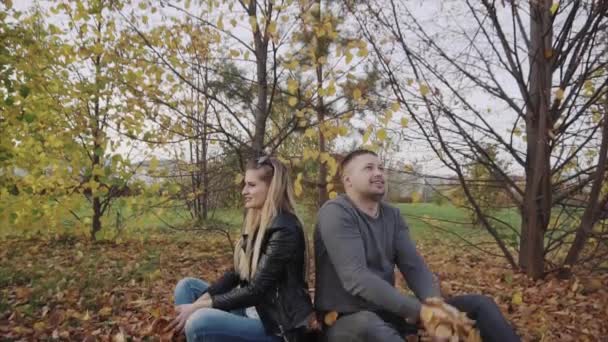 Junges glückliches Paar beim Spielen und Werfen von Blättern im Herbstpark — Stockvideo