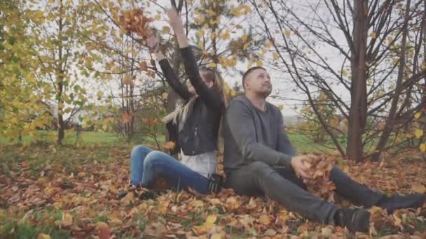 Unga lyckliga paret spelar och kasta löv i parken hösten — Stockvideo