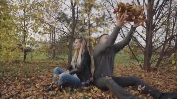 Jeune couple heureux jouant et jetant des feuilles dans le parc d'automne — Video