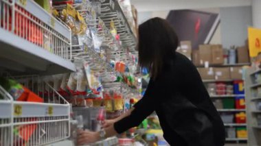 Bir süpermarkette kadın anne çocuk beslenme için küçük bir şişe seçer