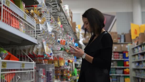 Mooie jonge vrouw kiest een fopspeen voor het kind in de supermarkt. — Stockvideo