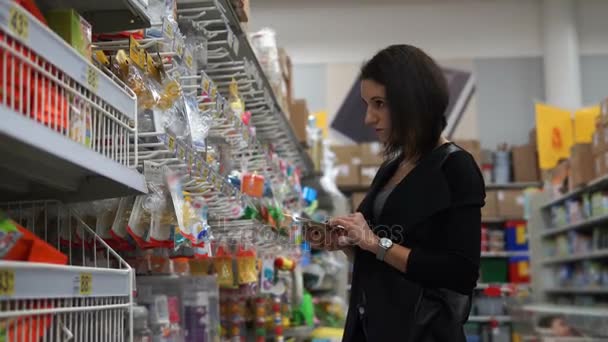 Hermosa joven mujer elige un maniquí para el niño en el supermercado . — Vídeos de Stock