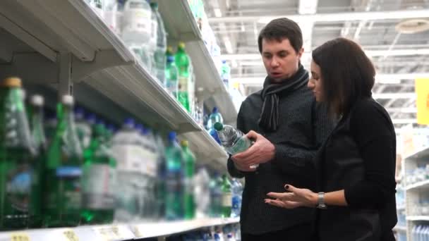 Casal jovem com entusiasmo escolher água mineral para uso doméstico . — Vídeo de Stock
