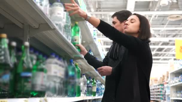 Casal jovem comparar duas garrafas de água . — Vídeo de Stock