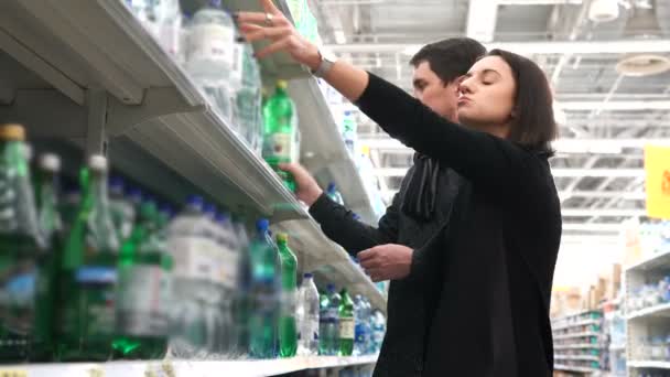 Pareja joven compara dos botellas de agua . — Vídeo de stock