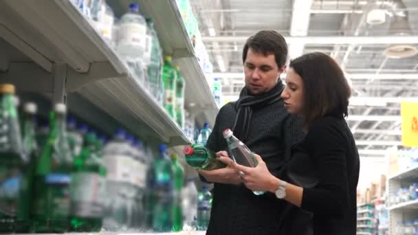 Jonge vrouw en haar echtgenoot kiezen mineraalwater. — Stockvideo