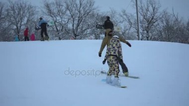 Volzhskii, Rusya Federasyonu - 8 Ocak 2017: Bir kız özel takım elbiseli bir kayak merkezinde onun snowboard, onun tarafından geçen diğer snowboard haddelenmiş.