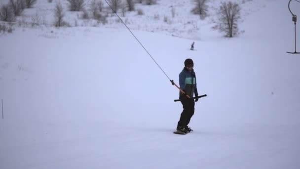 Юный спортсмен на сноуборде на склоне поднимается на Т-бар . — стоковое видео