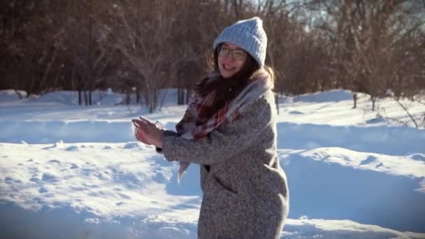 Chica alegre que se divierte día de invierno soleado. Ella lanza una bola de nieve a su amigo . — Vídeos de Stock