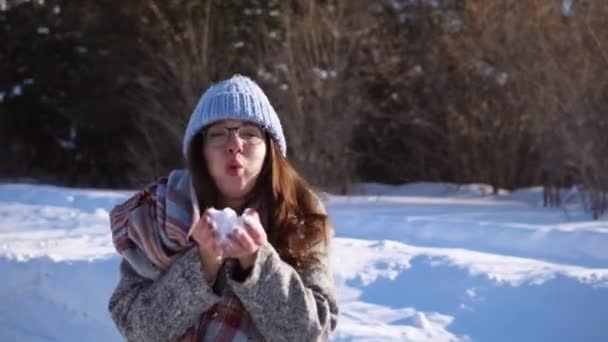 Девушка в зимнем лесу весело. Брюнетка выливает снег из рук . — стоковое видео