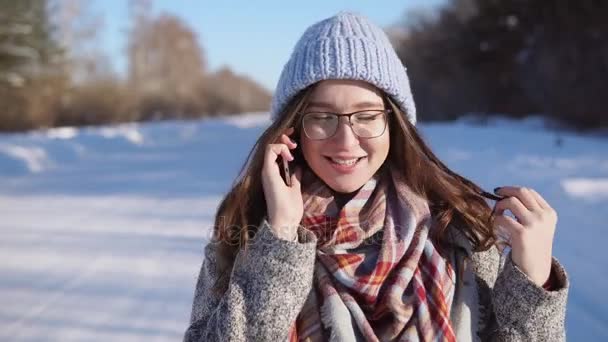 Mujer joven de pie en la carretera de invierno, ella está hablando por teléfono en el día soleado . — Vídeos de Stock