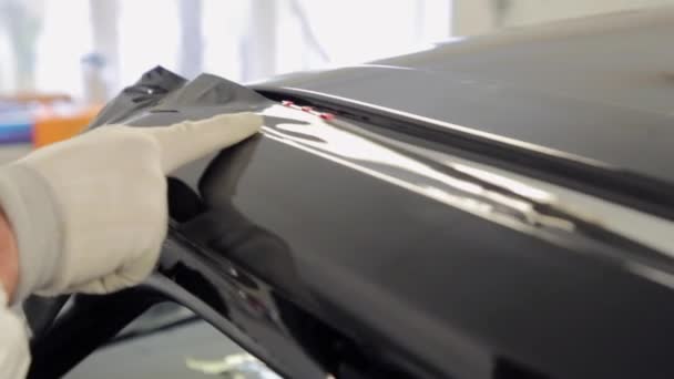 En skicklig i body shop tillämpar vinyl yta till mitten av fordonet. — Stockvideo