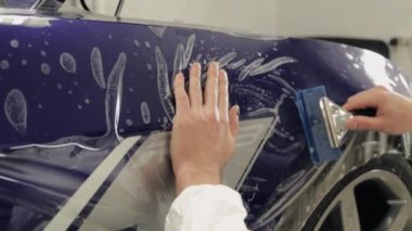Servis istasyonu işçi yapıştırın vinil pahalı bir araba.