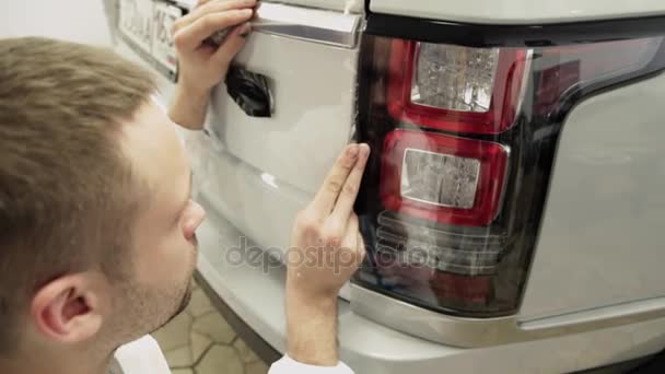 Close up shot of mans hands unstick the film with white cowl expensive car. — Stock Video