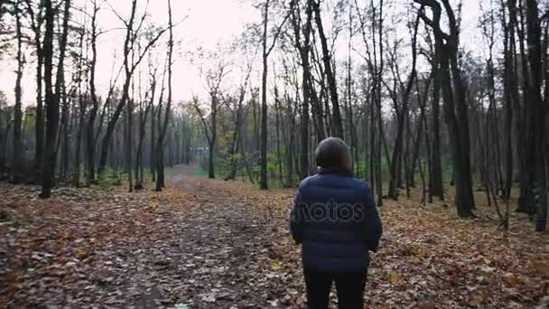 Lonely adult woman, dressed in warm autumn jacket walking in the autumn forest. — Stock Video