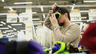 Süpermarkette snowboard denemede genç adam gözlük.