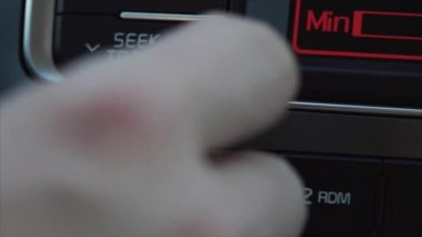 Genç bir adam arabada müzik ses ayarlar.