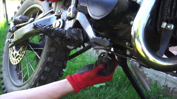 Мужчина во дворе закручивает винт в мотоцикле инструментом . — стоковое видео