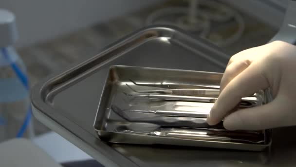 La mano di dentista con guanti prende un piccolo specchio e pinzette da vassoio per strumenti . — Video Stock