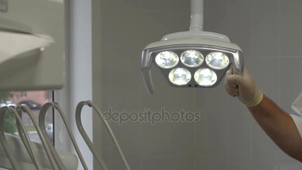 Close-up shot van de tandartsen hand bewegingen tandheelkundige lamp. — Stockvideo