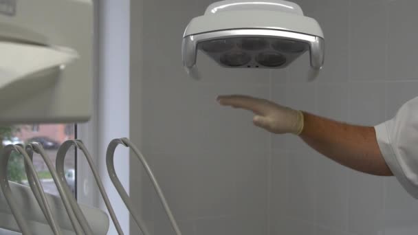 Close up shot of the dentists hand turns on dental lamp by the sensor touch . — Vídeo de Stock