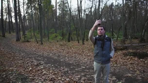 Homem adulto caminhando na floresta de outono. Turista faz fotos em um novo lugar . — Vídeo de Stock