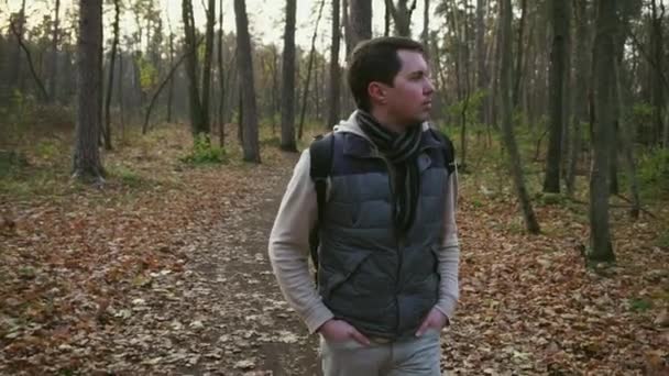 Молодой человек прогуливается по осеннему лесу . — стоковое видео
