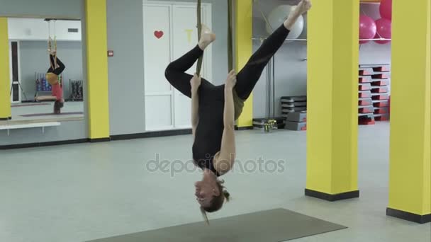 Befälhavaren på yoga göra en inverterad pose som hänger på en hängmatta tejp för aerial yoga — Stockvideo