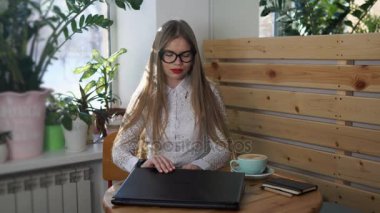 Bir kafede otururken bir dizüstü genç sevimli kadın açar.