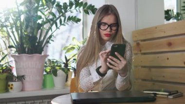 Güzel bir Yöneticisi bir akıllı telefon üzerinde bir arkadaşıyla öğle yemeği molası sırasında yeniden yazar