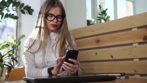 Mujer de negocios comprueba noticias del mundo en su teléfono móvil, en su mano un reloj inteligente — Vídeo de stock