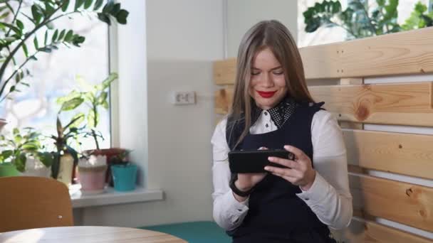 Mujer hermosa se ve la red social en su teléfono móvil con una sonrisa — Vídeos de Stock