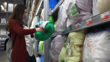 Genç kadın hipermarket onun yeni daire için bir yastık seçer.