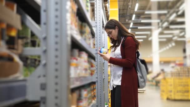 Mladá žena volba plechovky kukuřice v hypermarketu. — Stock video