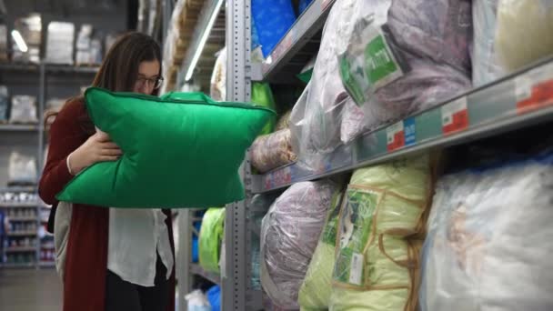 Νεαρή γυναίκα επιλέγει ένα μαξιλάρι για το νέο σπίτι της στο σούπερ μάρκετ. — Αρχείο Βίντεο