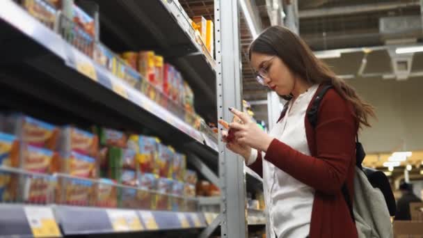 Joven bonita mujer elige galletas en el departamento de comestibles en el supermercado . — Vídeos de Stock