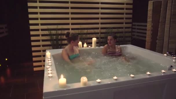 Две женщины болтают в ванной о спа-процедурах, которые они могут получить в спа-салоне — стоковое видео
