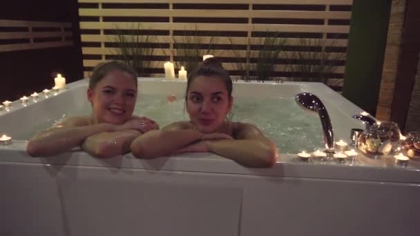 Två flickor som kommer till hälsocentret njuta av vattenbehandlingar i jacuzzin. — Stockvideo