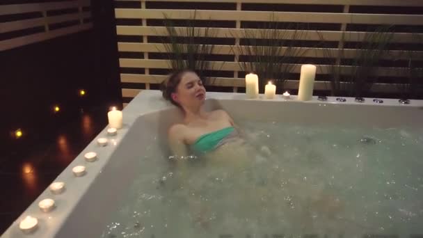 Uma jovem jaz em um jacuzzi com sal marinho, e descansa depois de um dia difícil — Vídeo de Stock