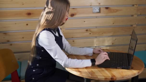 Zakenvrouw doorbladert nieuws op laptop op haar hand slimme horloge voor het controleren van mail — Stockvideo