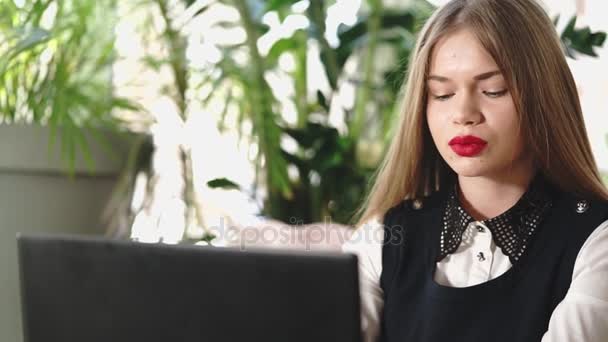Een jonge student ziet er via haar account in sociale netwerken, zittend in een caf — Stockvideo